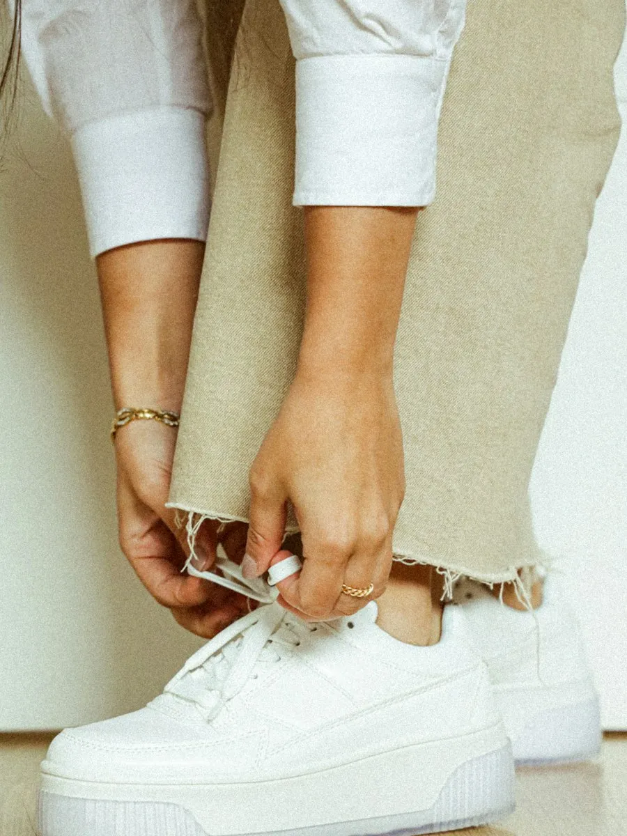 Mani che allacciano sneakers bianche